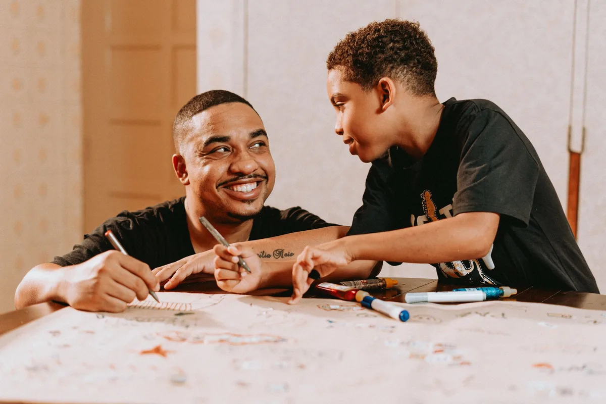 Un padre e hijo dibujando juntos en una mesa, compartiendo un momento de conexión y creatividad.