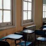 Aula vacía con pupitres sin estudiantes y materiales educativos dispersos