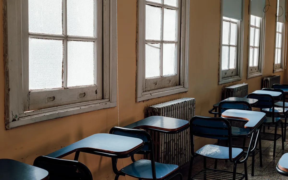 Aula vacía con pupitres sin estudiantes y materiales educativos dispersos