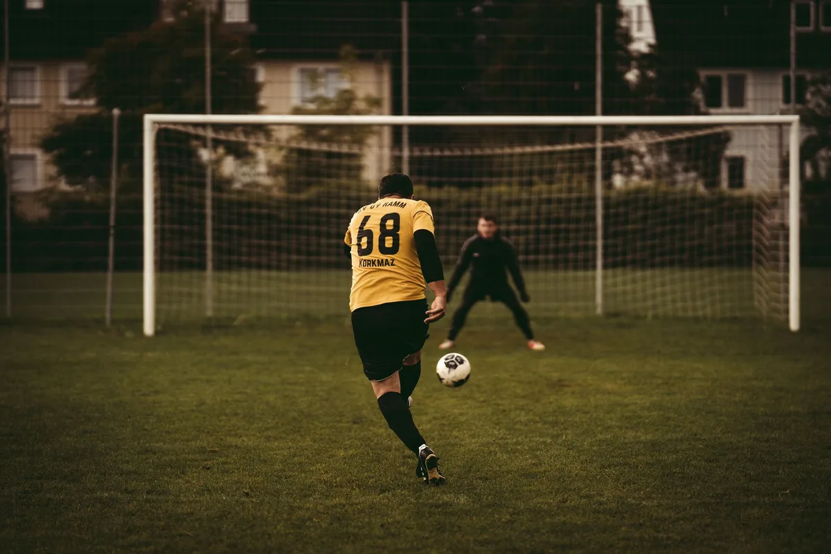Jugadores de fútbol en una tanda de penales, con el arquero preparado para detener el remate