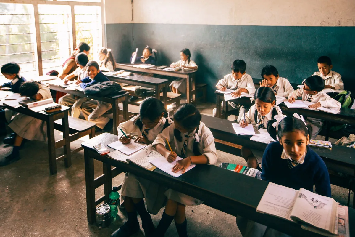 Aula vacía con escritorios y pizarra, luz matinal por las ventanas, sin estudiantes ni docentes presentes.