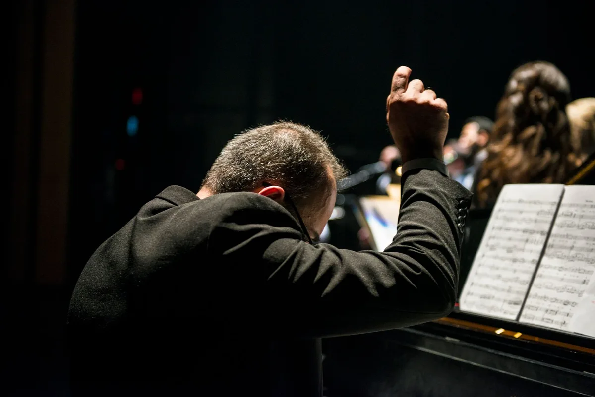 Pianista tocando en un escenario iluminado durante un concierto en vivo