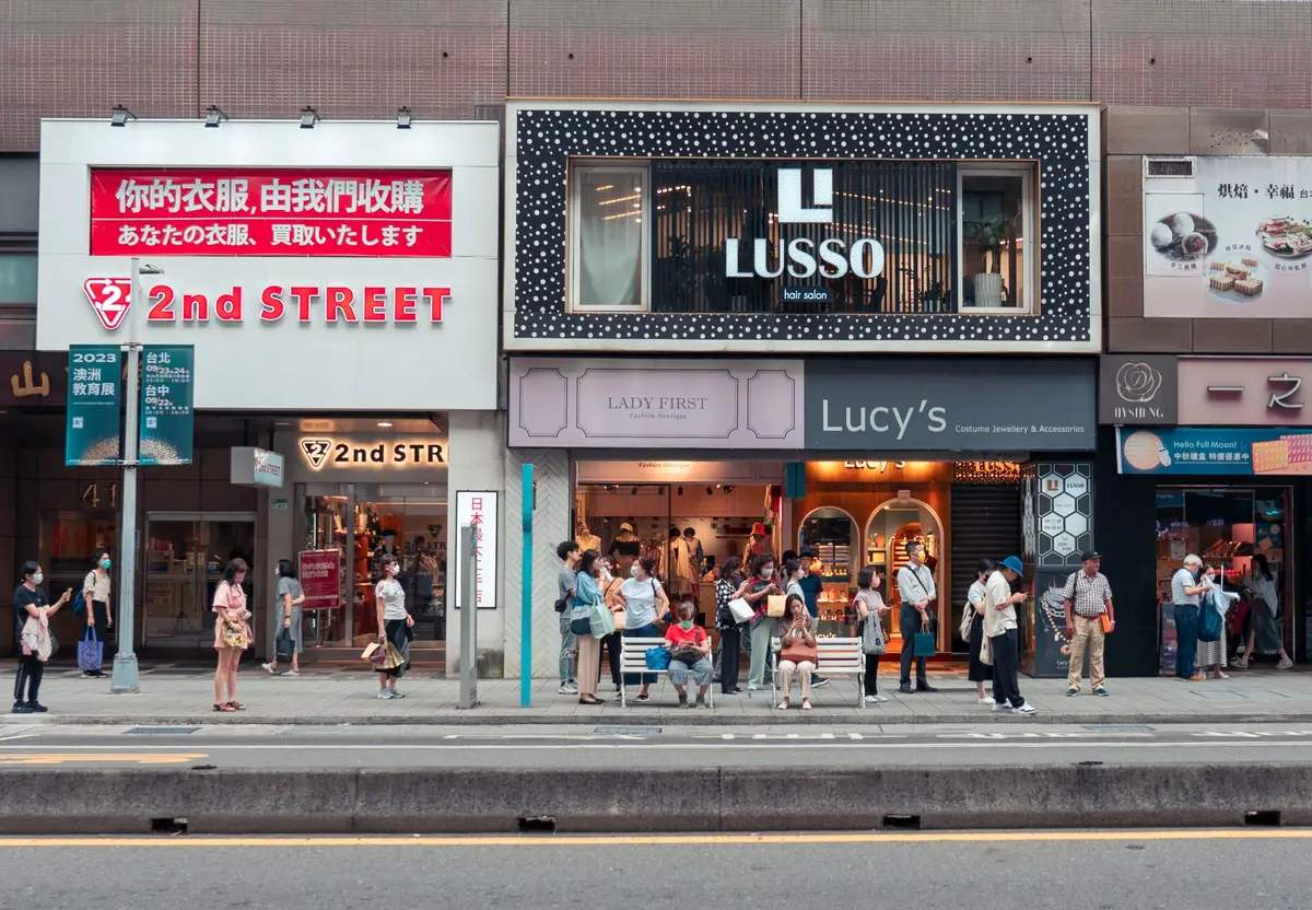 Calle comercial concurrida con tiendas y compradores