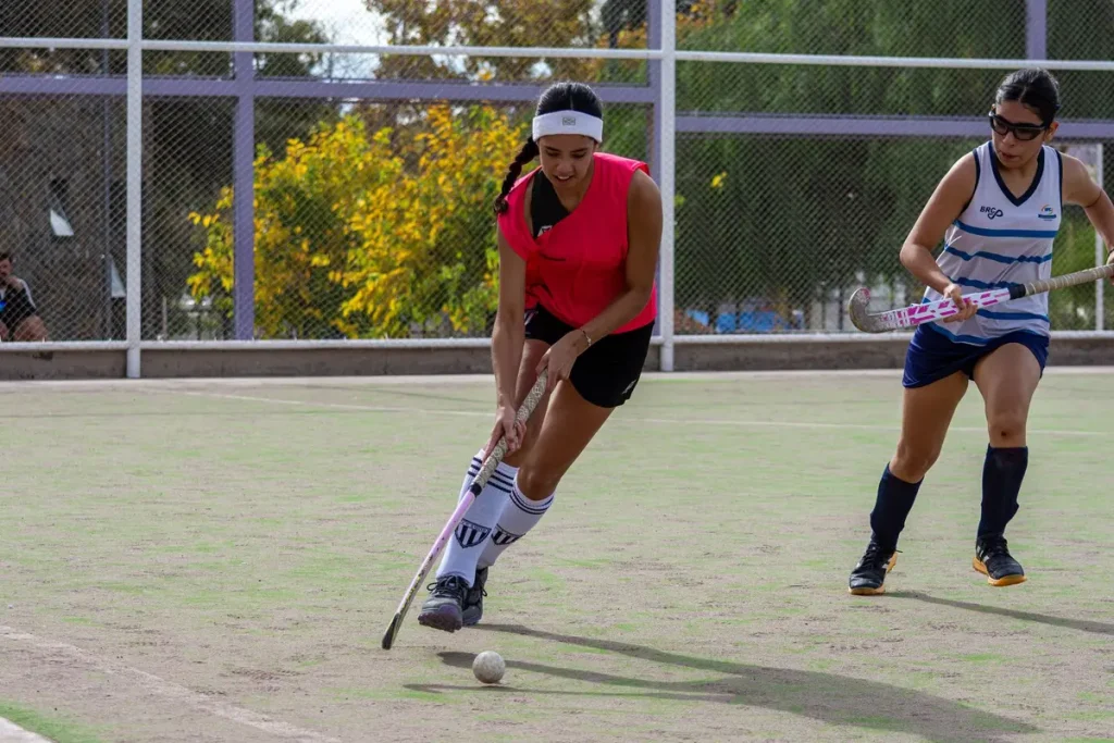 Jugadoras de hockey celebrando un gol en la cancha con los bastones en alto