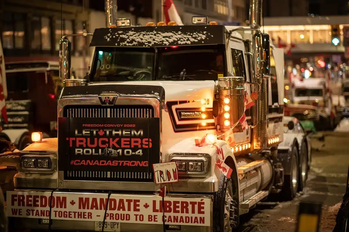 Camiones de carga estacionados sin actividad frente a una planta de acopio agrícola con trabajadores en protesta.