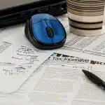 Documentos oficiales y declaraciones patrimoniales sobre un escritorio de oficina con escalas de justicia de fondo