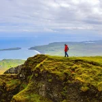 Excursionista contemplando un vasto paisaje de montañas y valles bajo luz dorada