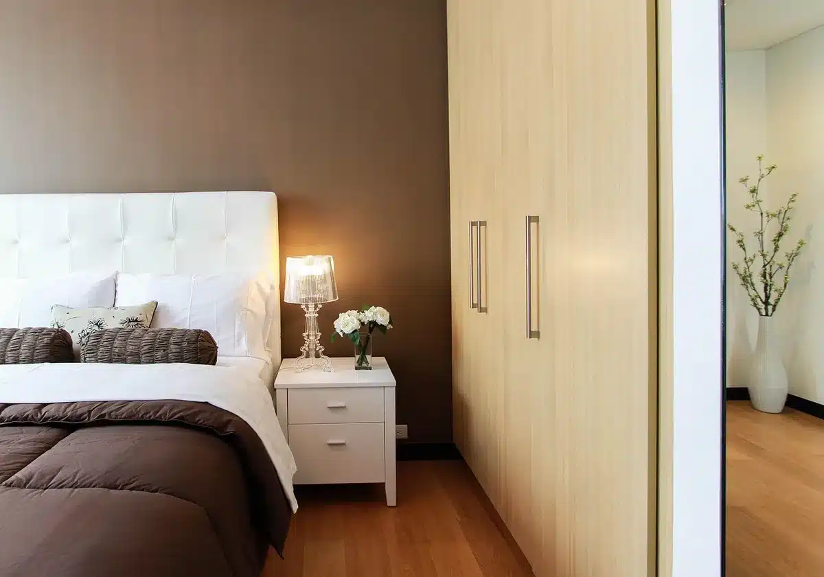 Cama hospitalaria con manos anónimas y luz tenue que evoca tensión sobre la salud