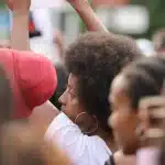 Multitud anónima en un microestadio con banderas y escenario al fondo