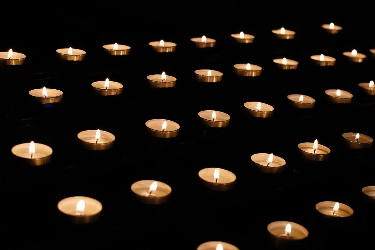Vigilia con velas y hojas borrosas frente a un edificio judicial en plaza