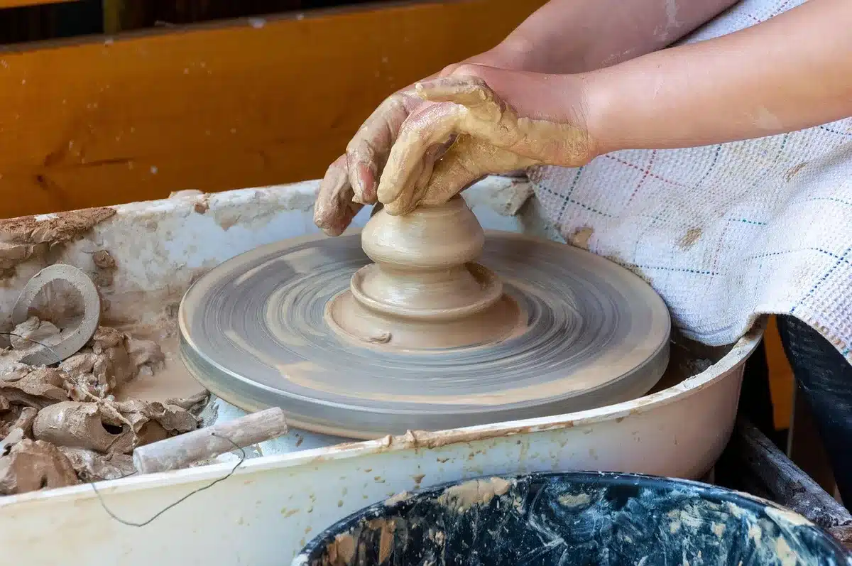 Estudio de radio con consolas encendidas y manos anónimas ajustando perillas