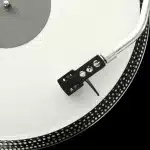 Tocadiscos vintage con cintas de estudio y baqueta sobre una mesa, evocando grabaciones rescatadas